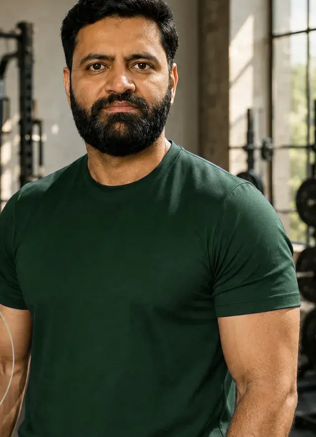 Nabeel in a sunlit gym, wearing a navy training shirt and looking calmly at the camera.