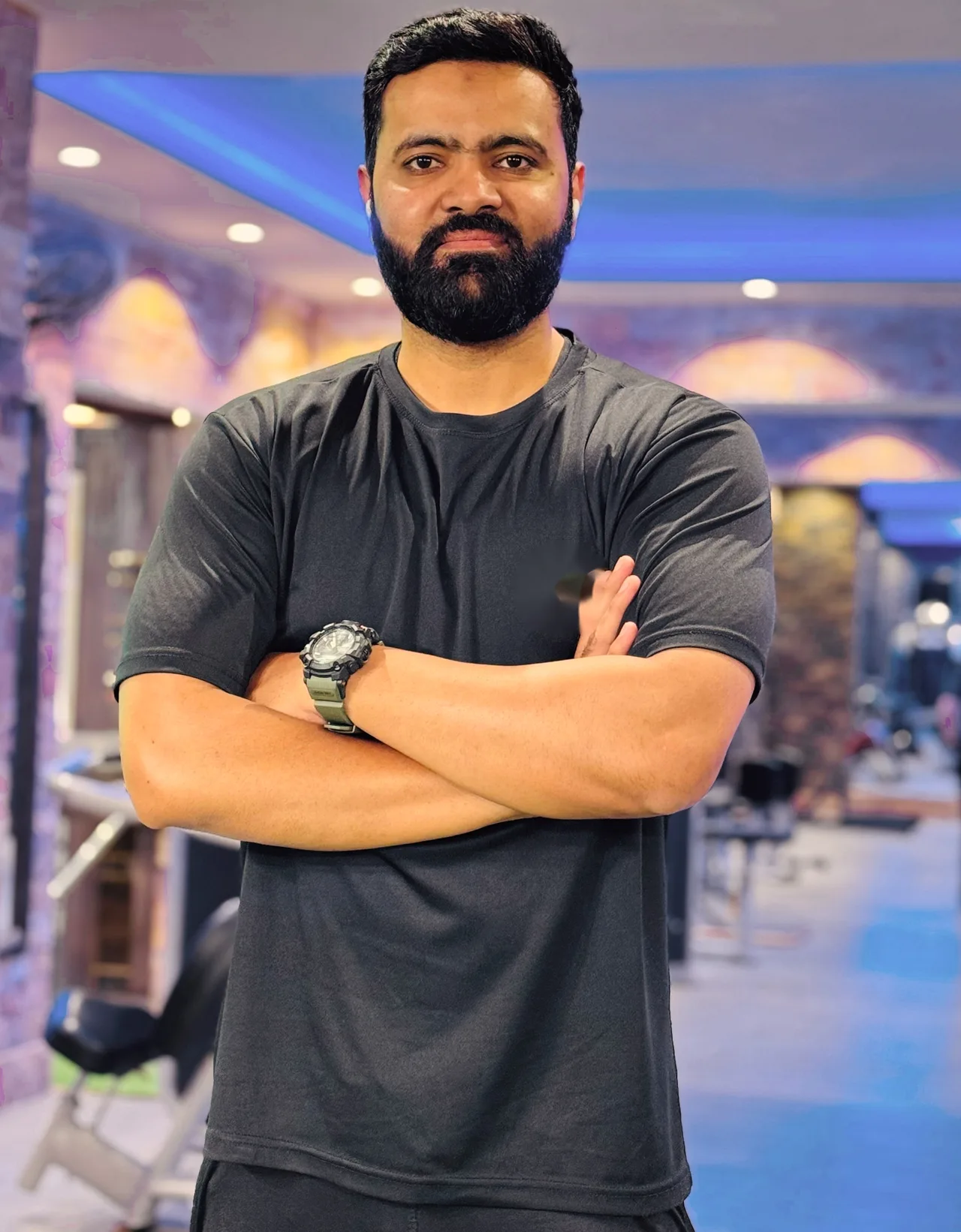 Nabeel Baig standing with arms crossed in a gym, looking calmly at the camera.